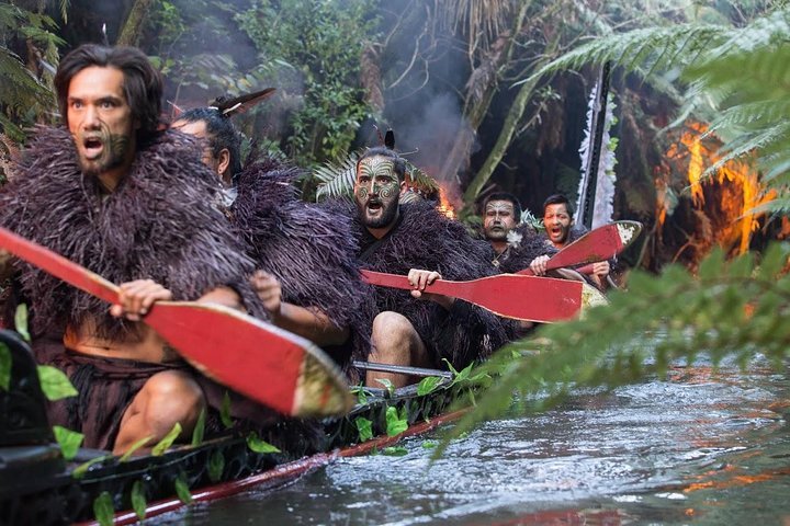 Experience the intensity of Māori culture as warriors paddle down the Wai-o-Whiro stream showcasing rich traditions and rituals amid lush surroundings and the sounds of ancient instruments.
